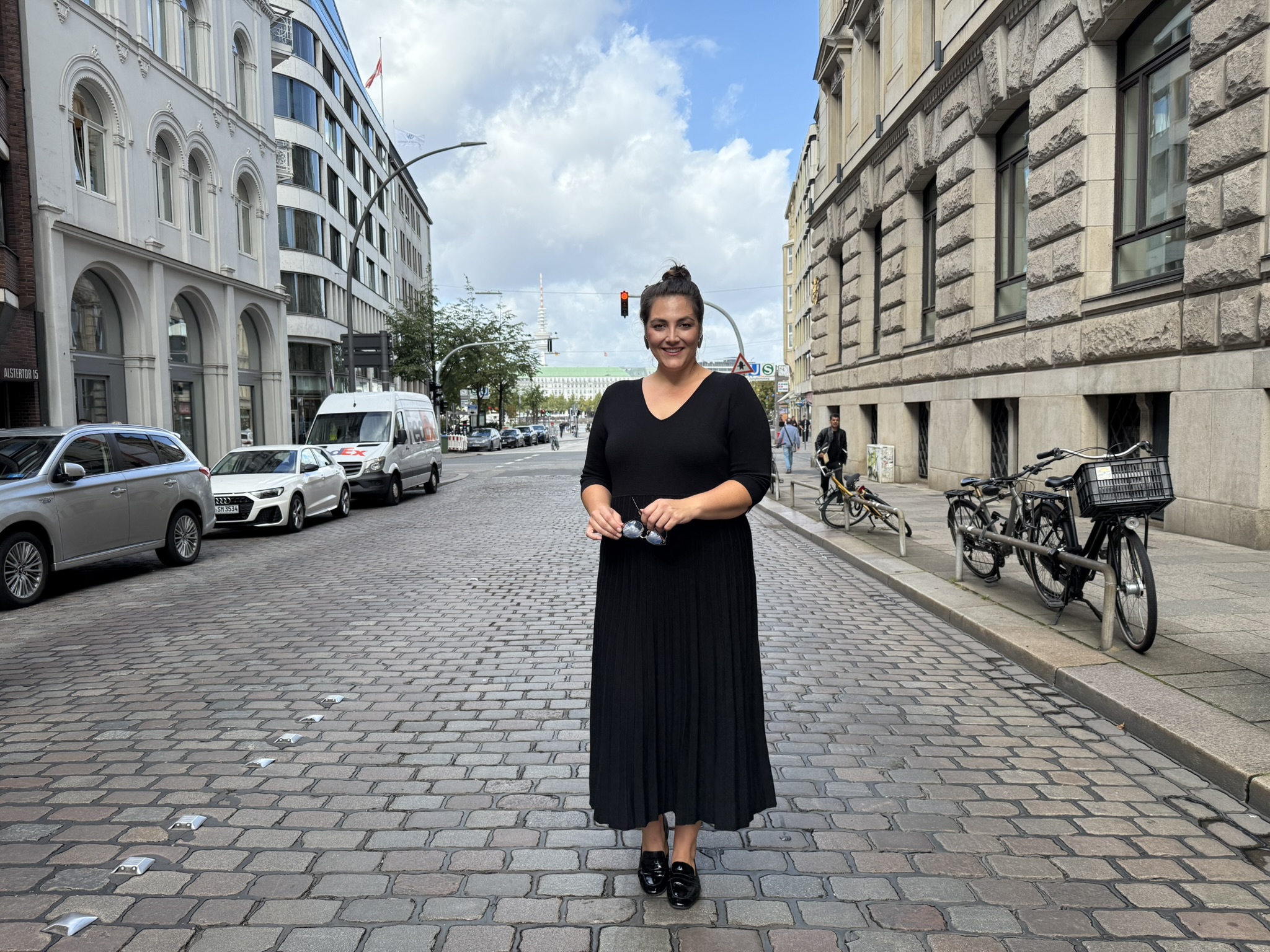 Frau trägt ein elegantes schwarzes Kleid in der Innenstadt – moderne Abendkleider große Größen Köln für stilbewusste Anlässe.