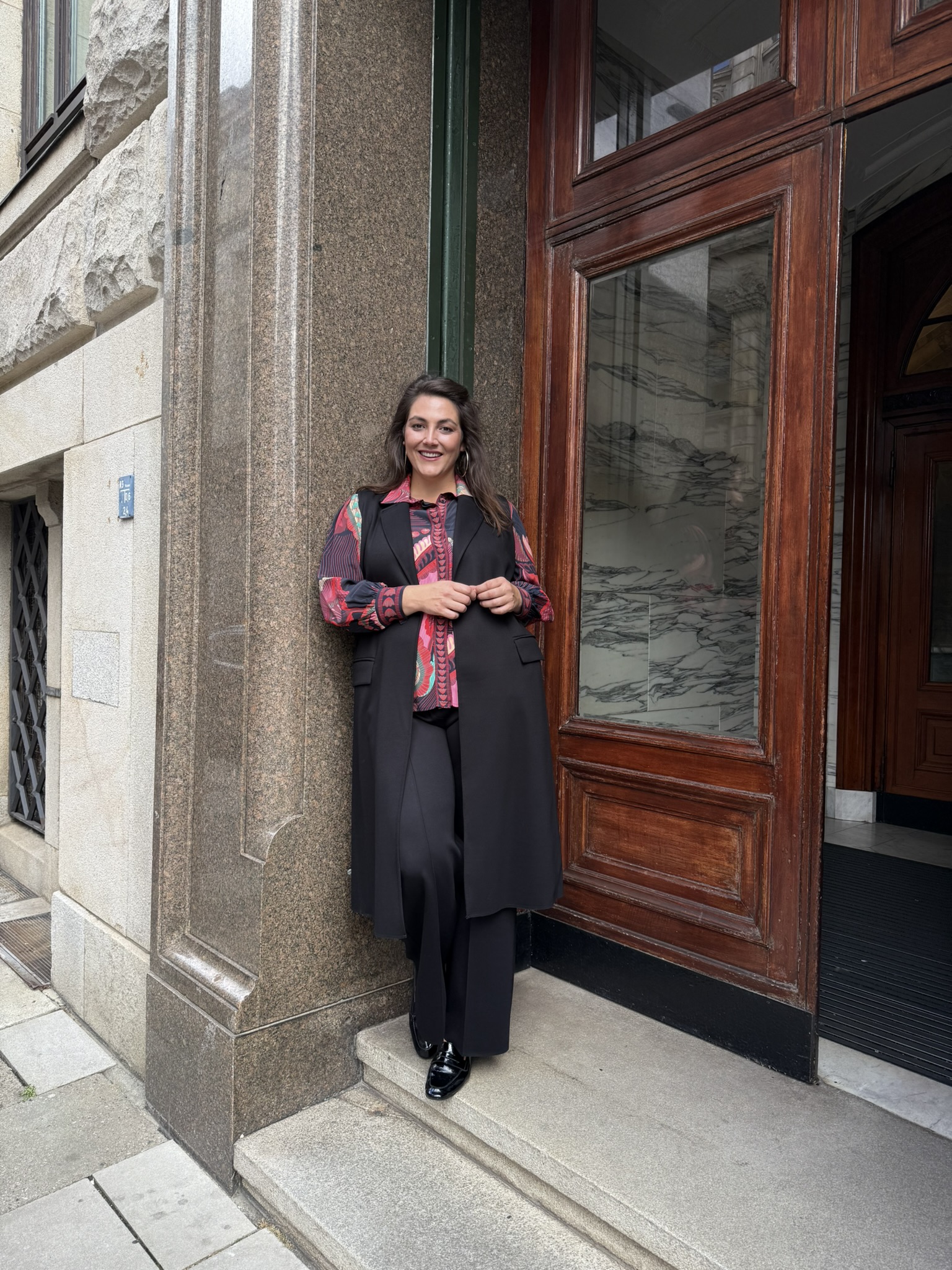 Elegante Abendmode für große Größen in Düsseldorf vor einem historischen Hauseingang.