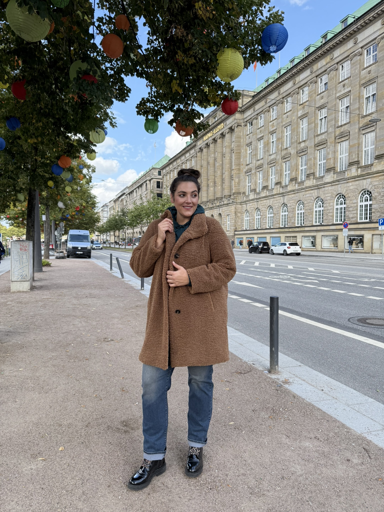 Frau trägt braunen Mantel und Jeans in der Innenstadt, moderne Mode für mollige Köln mit Stil, Komfort und Selbstbewusstsein.