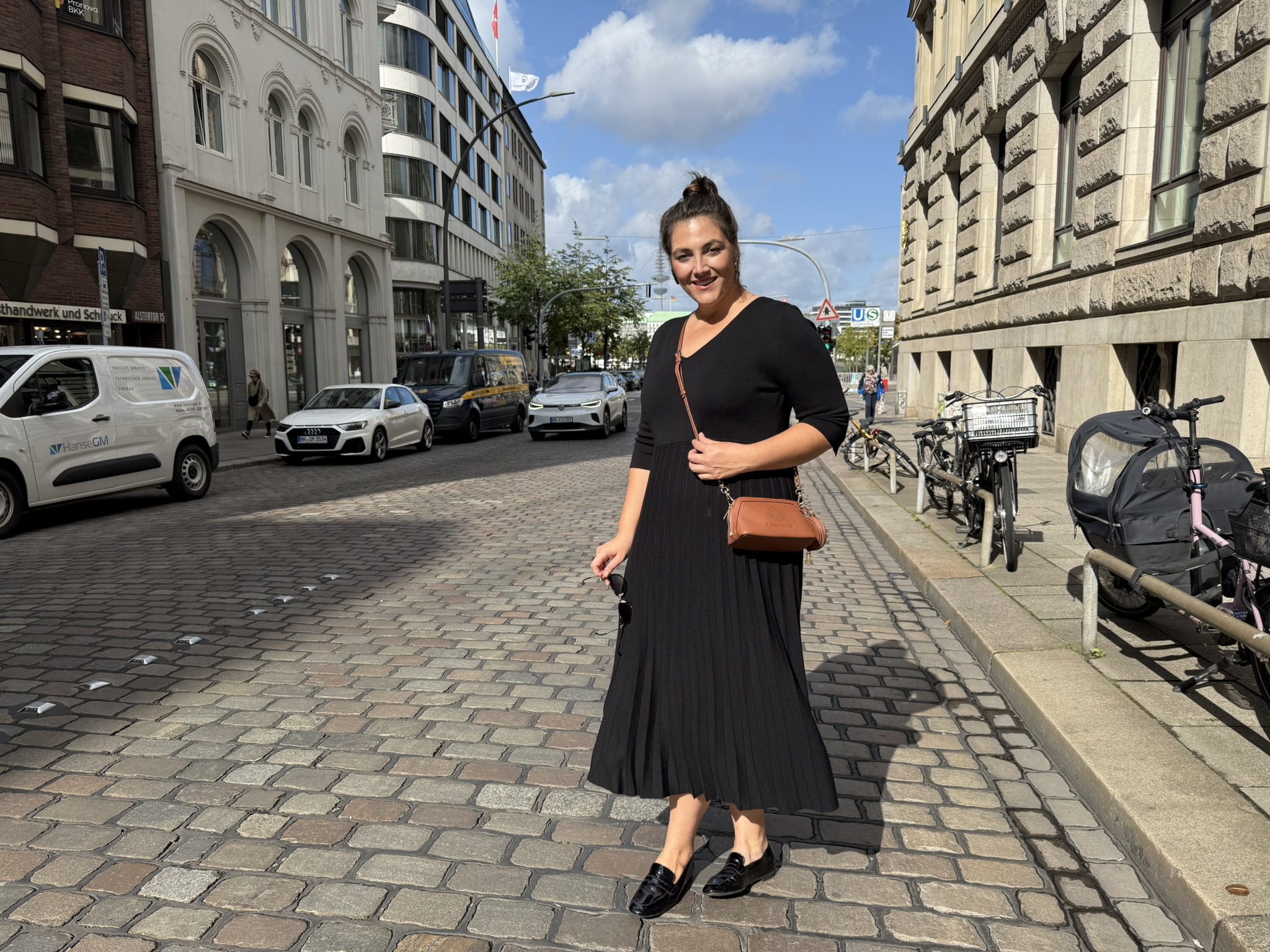 Frau trägt ein elegantes schwarzes Kleid in der Stadt, Abendkleider große Größen München für moderne, selbstbewusste Frauen.