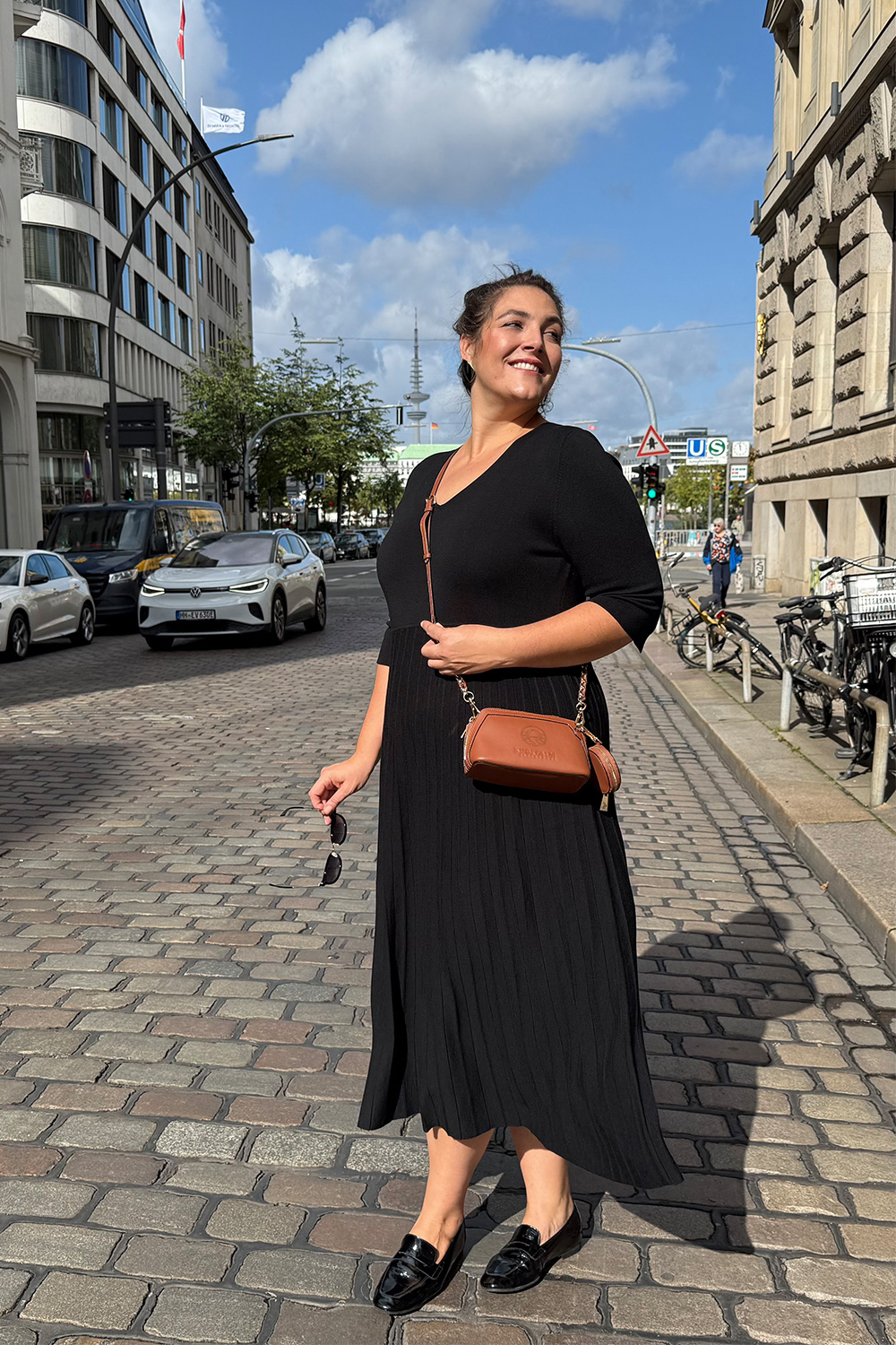 Elegantes schwarzes Kleid in Abendmode für große Größen in Mannheim auf der sonnigen Innenstadtstraße