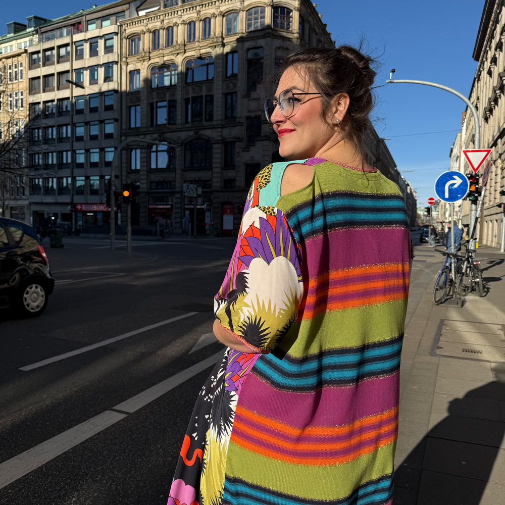 Frau in farbenfrohem Kleid auf einer Dortmunder Innenstadtstraße, große größen damen dortmund in modernem, ausdrucksstarkem Stil.