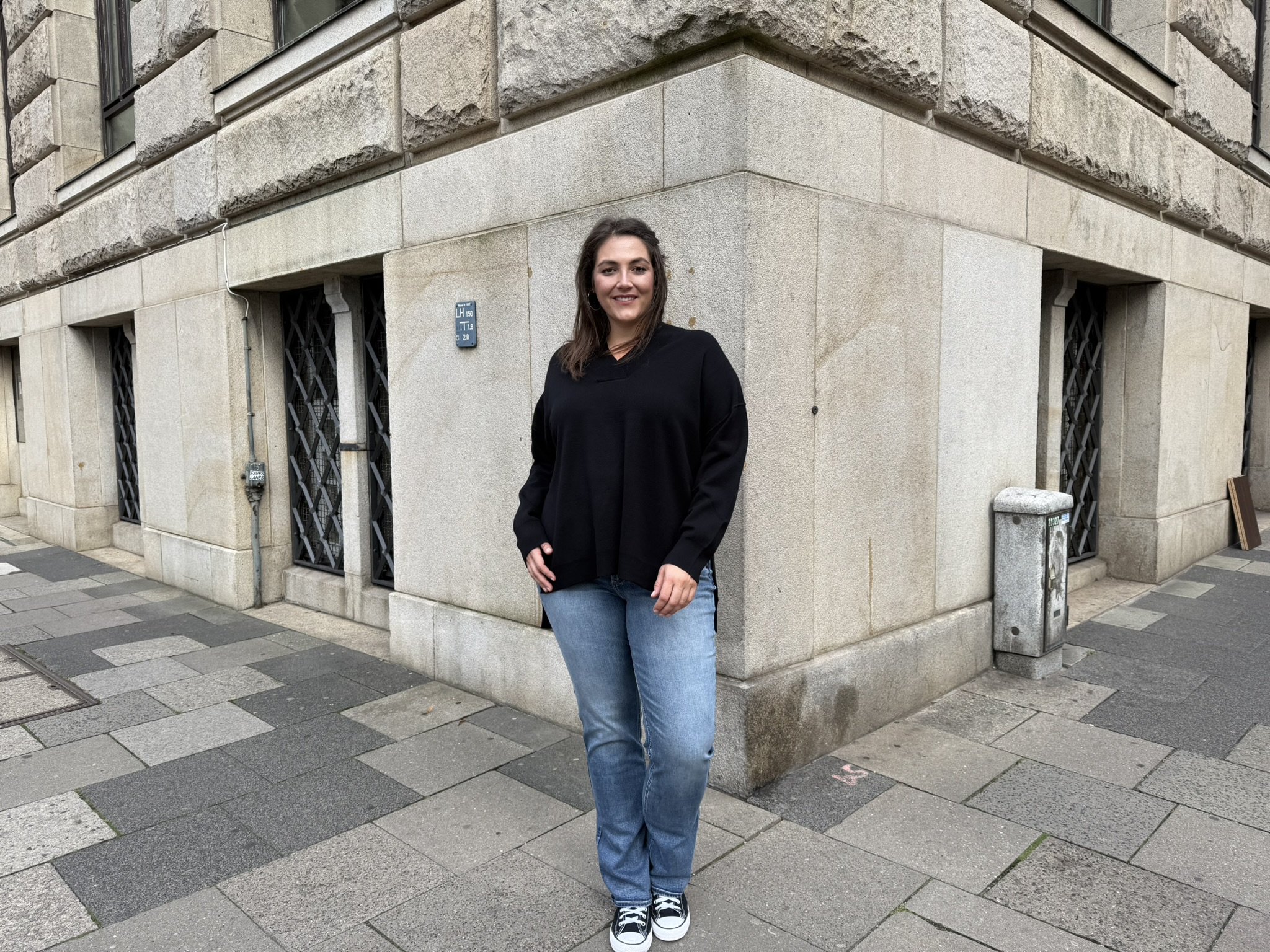 Frau trägt elegante Freizeitmode in großen Größen in der Innenstadt von Hannover, moderne Jeans und schwarzer Pullover, stilvolle Mode für mollige Hannover.