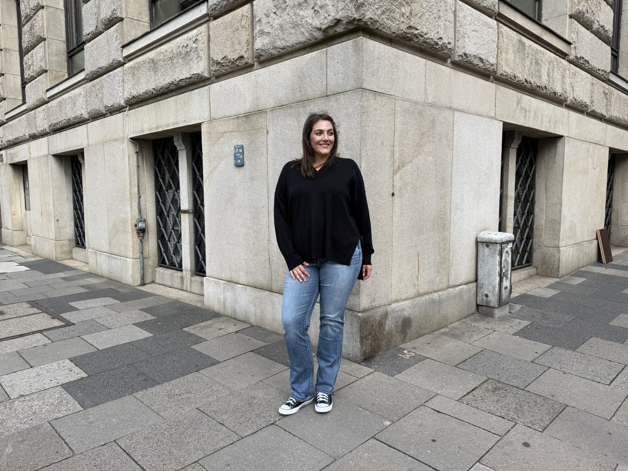 Frau in lässigem plus size Frankfurt Streetstyle vor historischer Gebäudefassade.