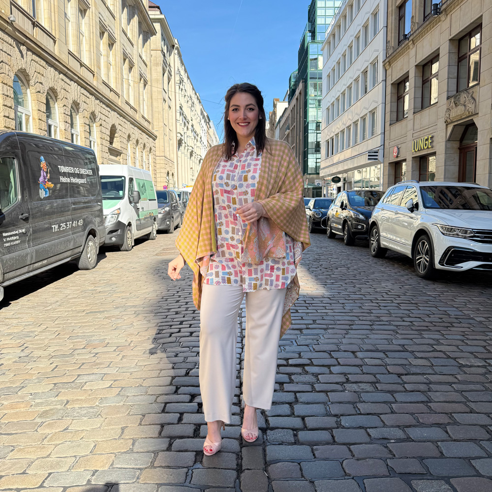 Braunschweig Bekleidung Übergrößen, Kundin in bunt bedruckter Bluse, cremefarbener Marlenehose und senfgelbem Karoponcho.