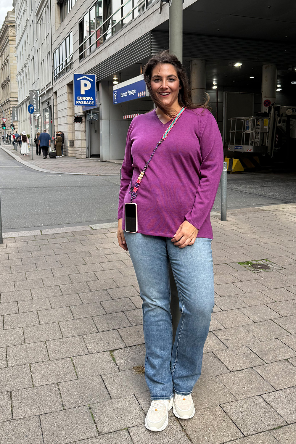 Damen Kleidung für dicke Wiesbaden am Beispiel eines Casual Looks mit pinkem Strickpulli und blauer Schlagjeans.