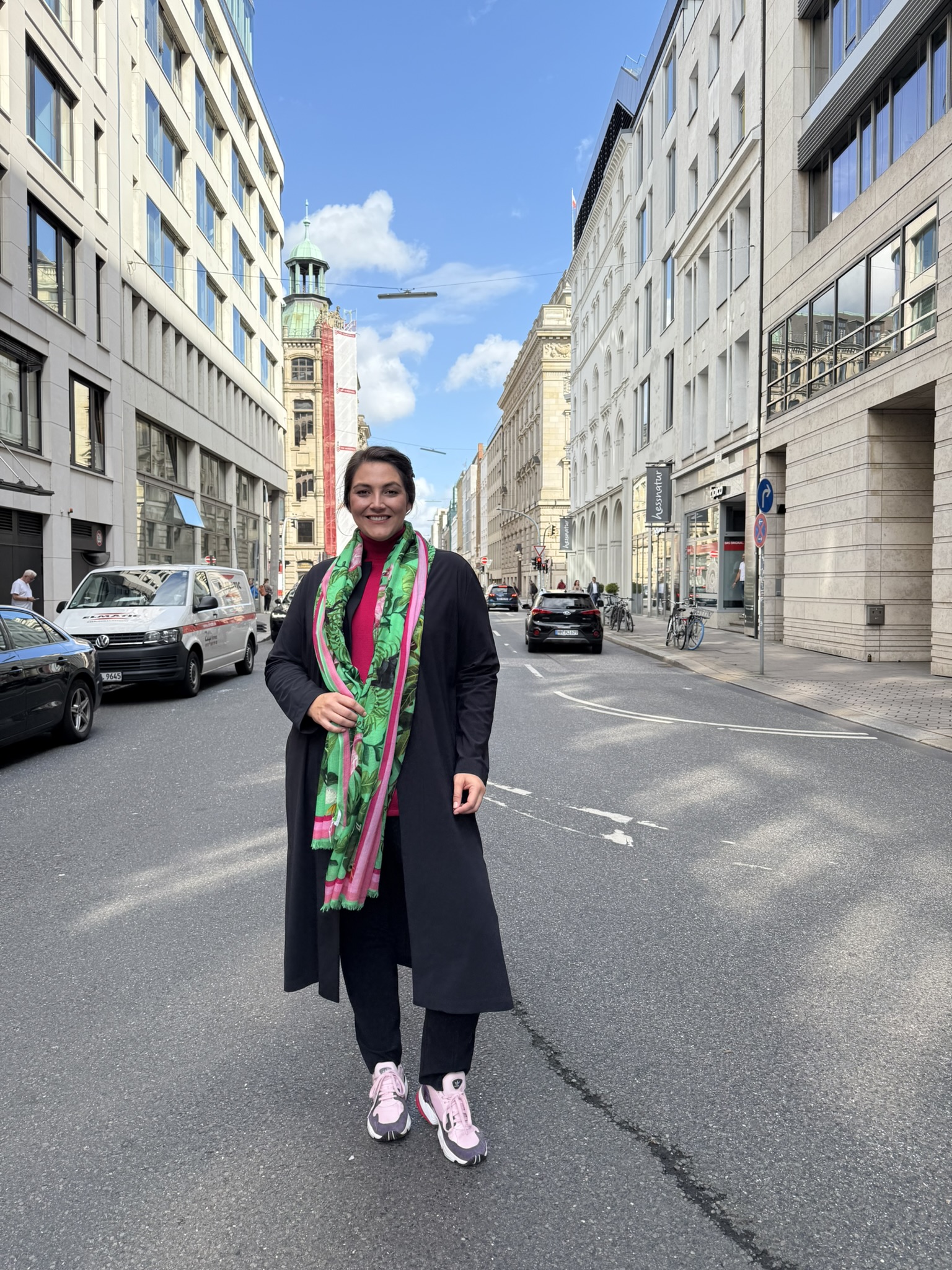 Damenmode große Größen Kiel, Kundin in pinkem Rollkragenpullover, schwarzem Longcardigan und grün gemustertem Schal.