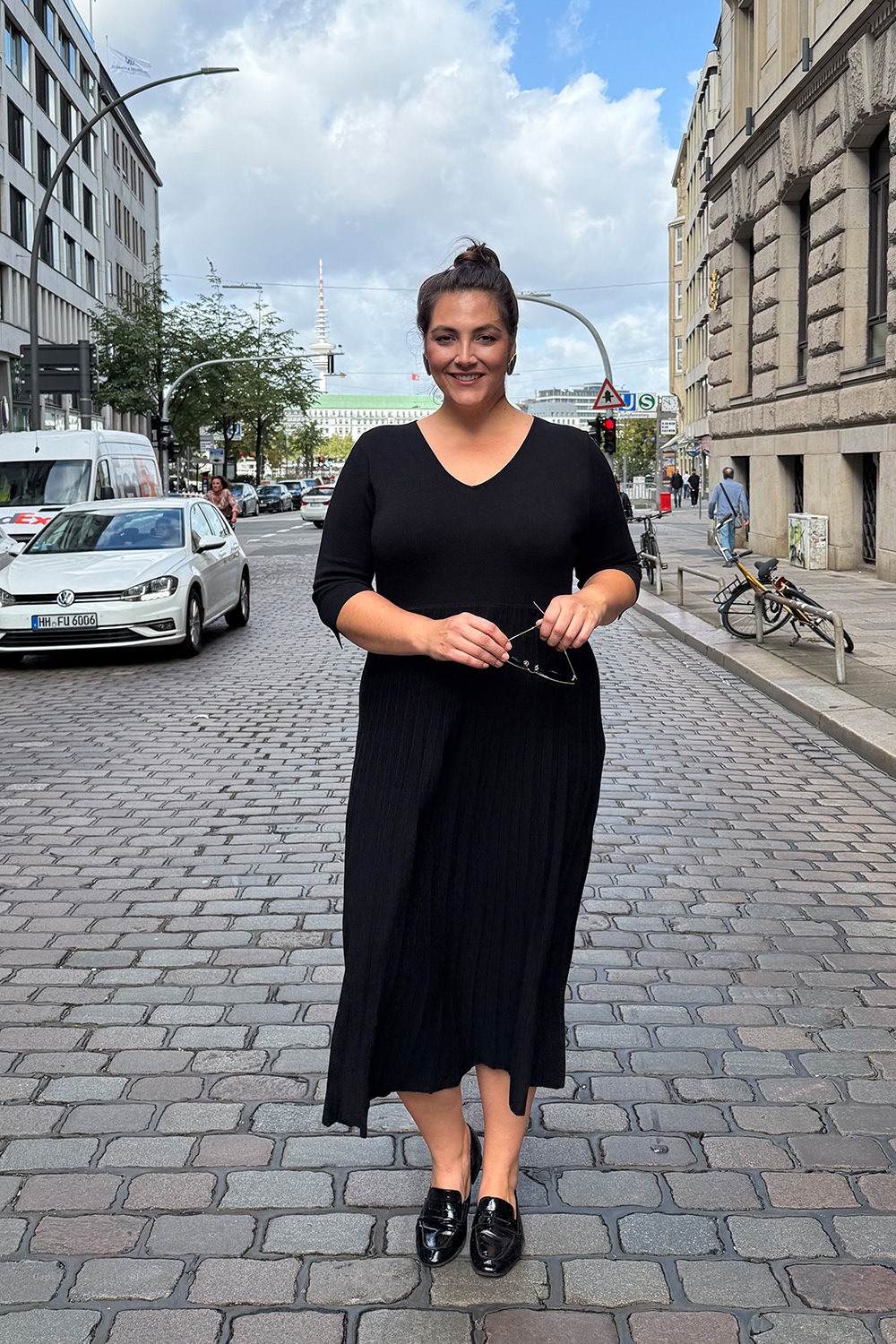 Kleidung für mollige Wiesbaden am Beispiel eines Strickkleids in Schwarz mit Plisseerock und 3 4 Ärmeln.