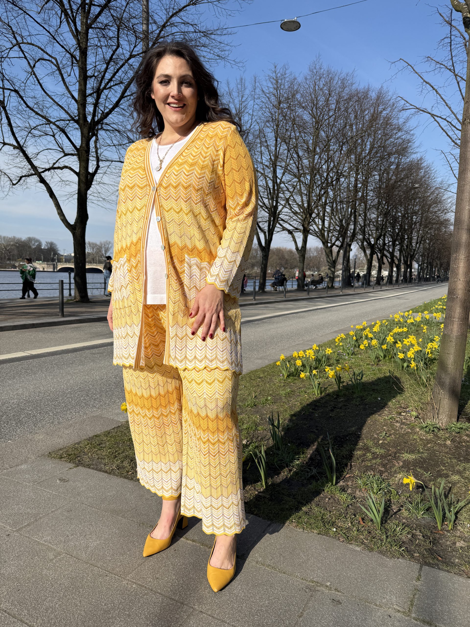 XXL Damenmode mit Farbe und Stil: Kundin in farbenfroher Chamäleon-Bluse und lila Stoffhose auf einer Hamburger Straße
