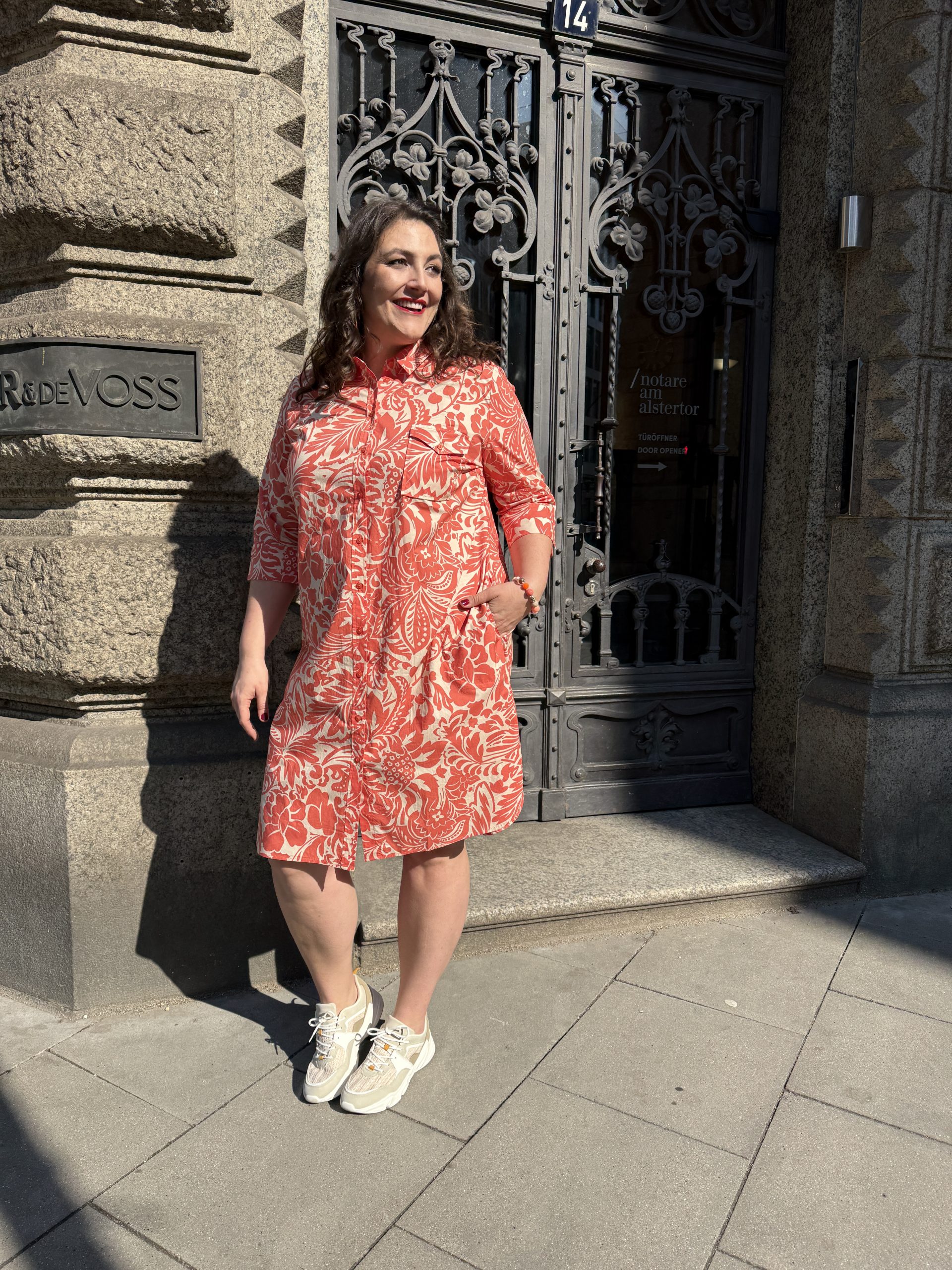 Übergrößen Frankfurt: Frau trägt rot-weißes Hemdblusenkleid mit Blumenprint und weißen Sneakers